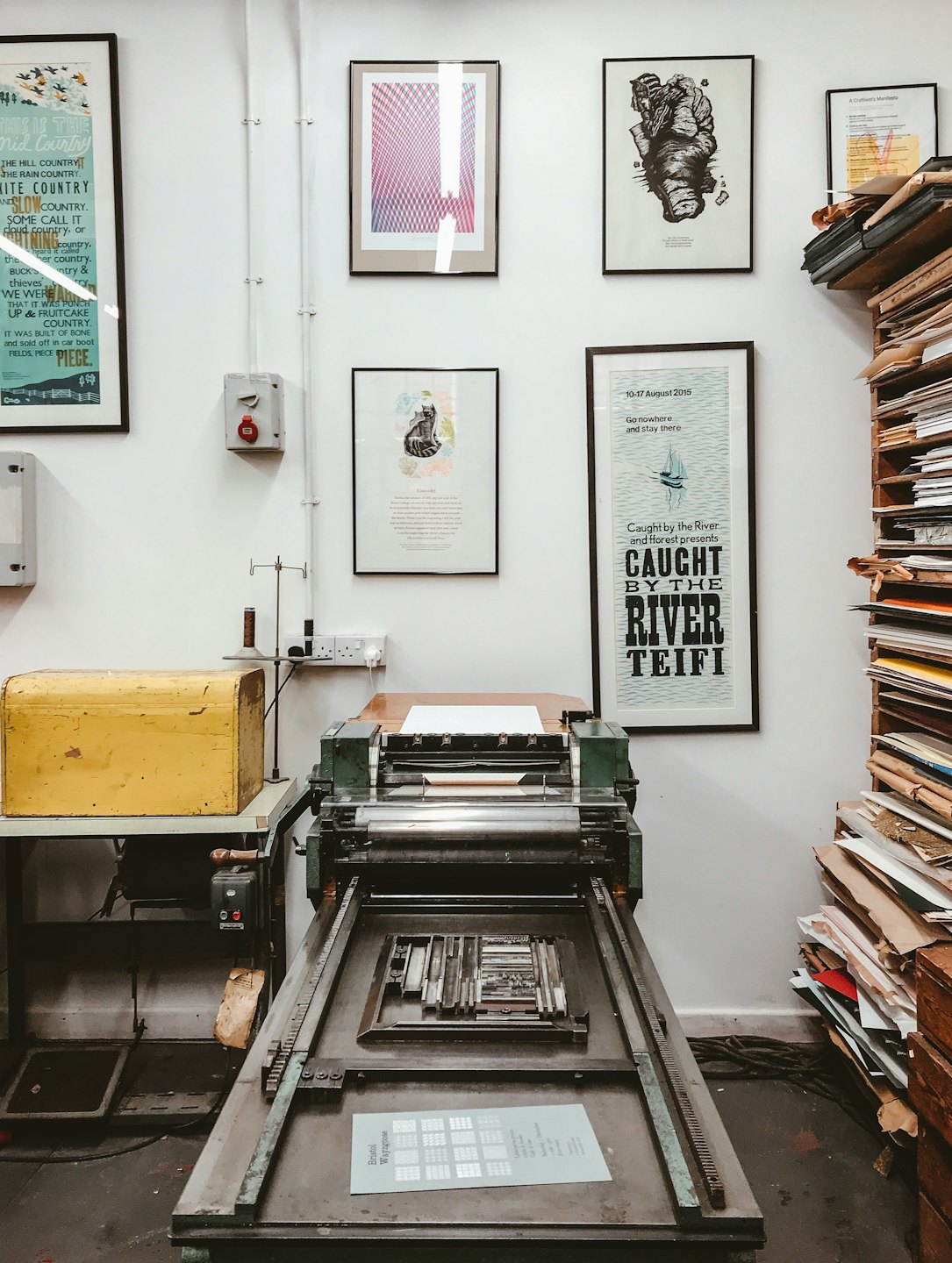 Duża, zabytkowa prasa drukarska letterpress z ustawionymi czcionkami do druku.
